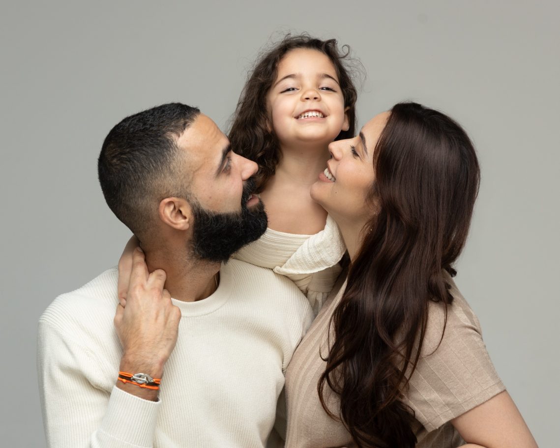 Famille souriante avec un père, une mère et une petite fille.